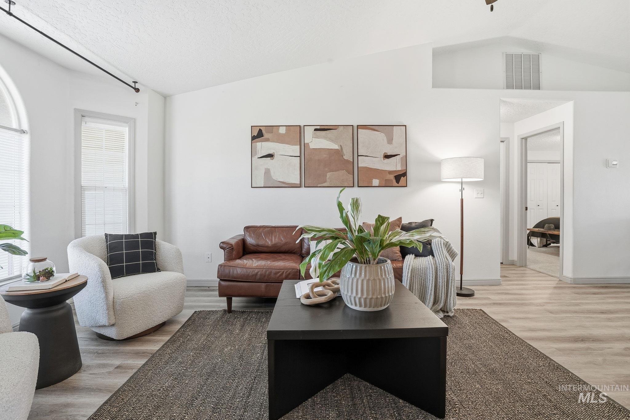 Living area featuring lofted ceiling, light wood-style floors, and a textured ceiling