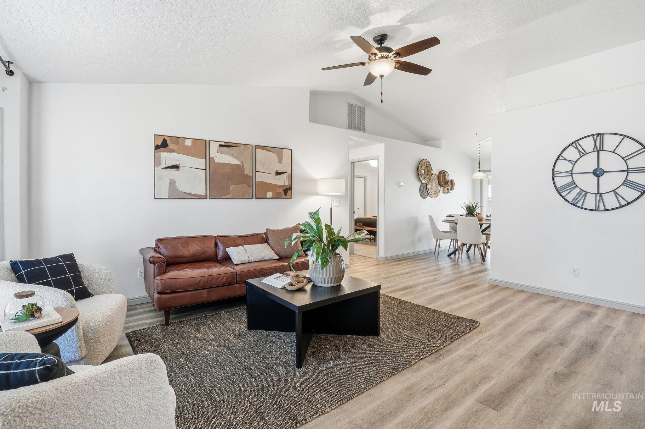 Living area with ceiling fan, wood finished floors, a textured ceiling, and lofted ceiling