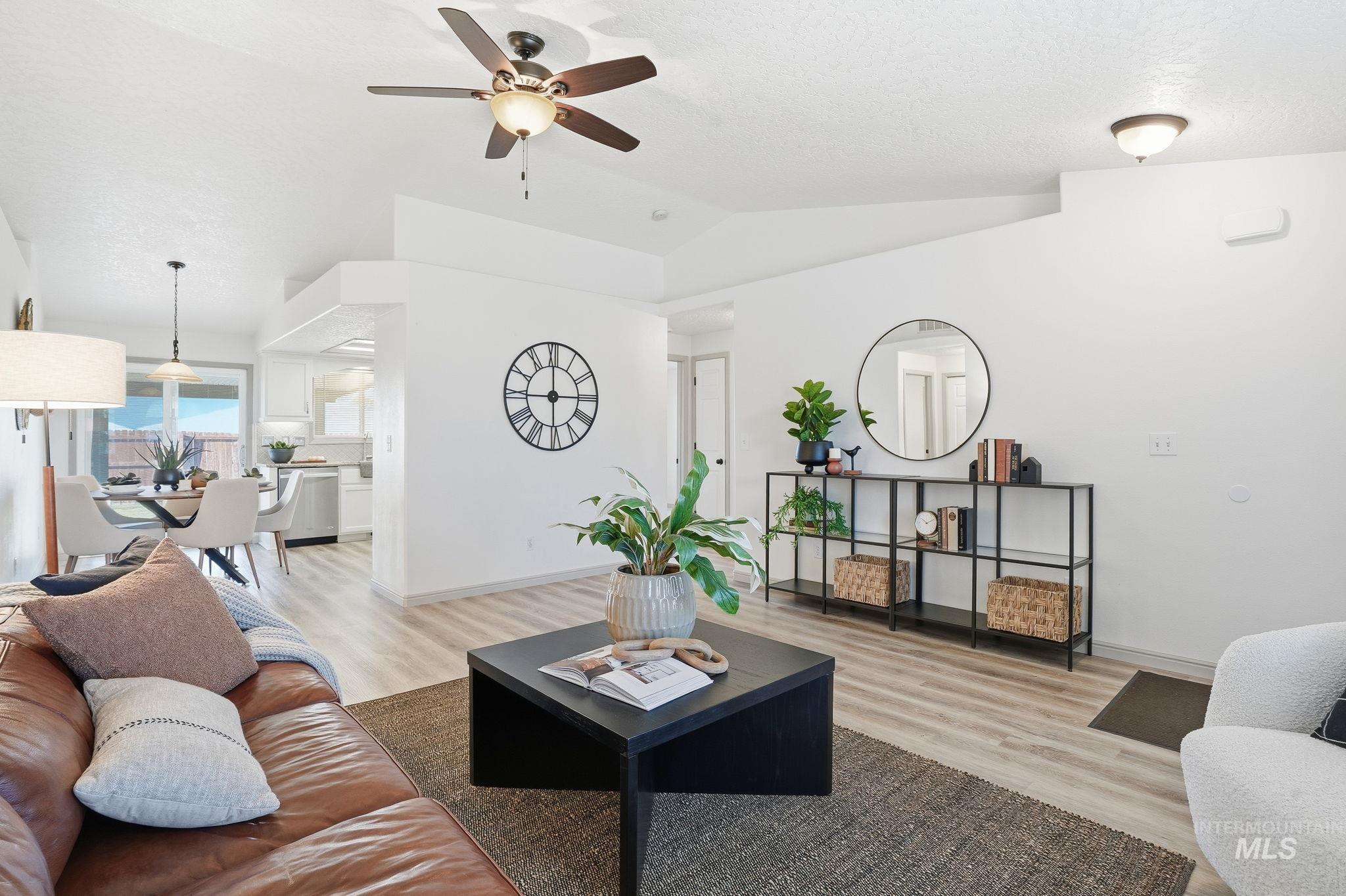 Living area with light wood finished floors, lofted ceiling, a ceiling fan, and a textured ceiling