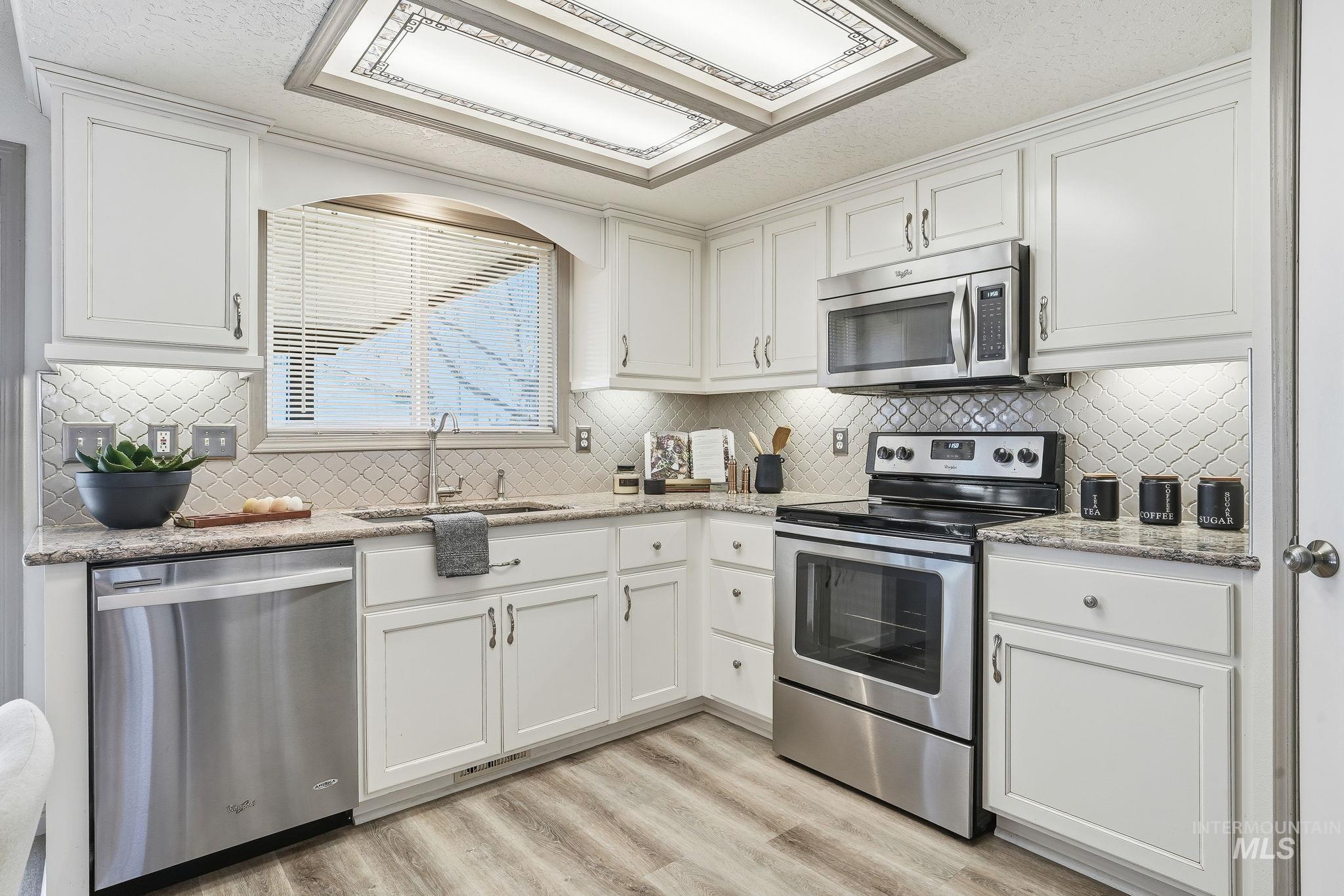Kitchen with stainless steel appliances, light stone counters, and backsplash