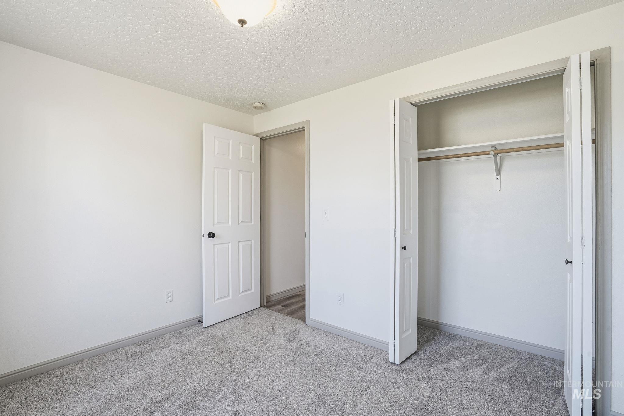 Unfurnished bedroom with a textured ceiling, light colored carpet, and a closet