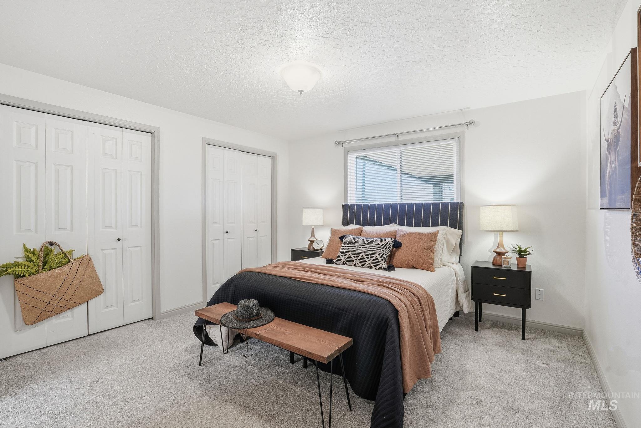 Carpeted bedroom with multiple closets and a textured ceiling