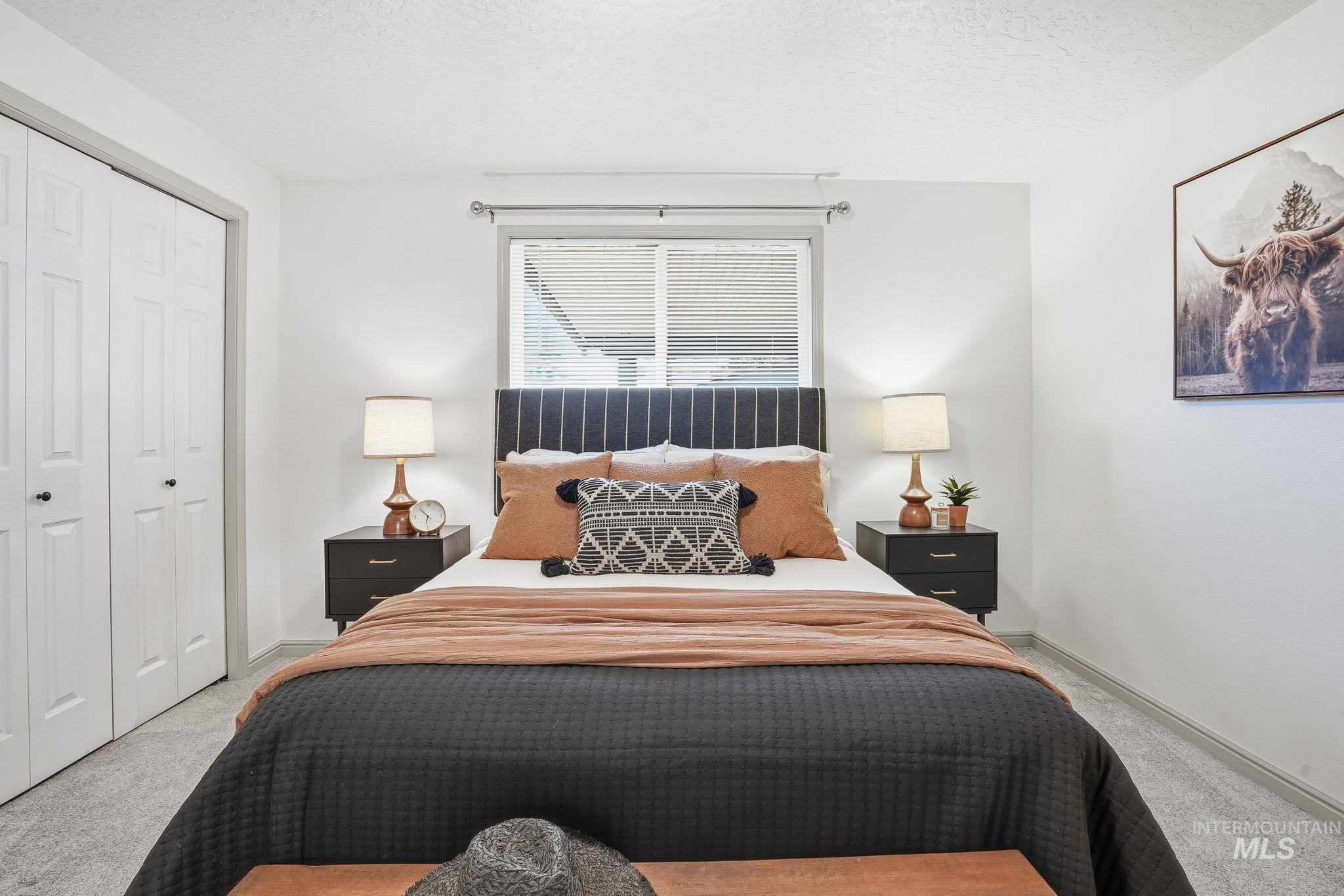 Bedroom with light carpet, a textured ceiling, and a closet