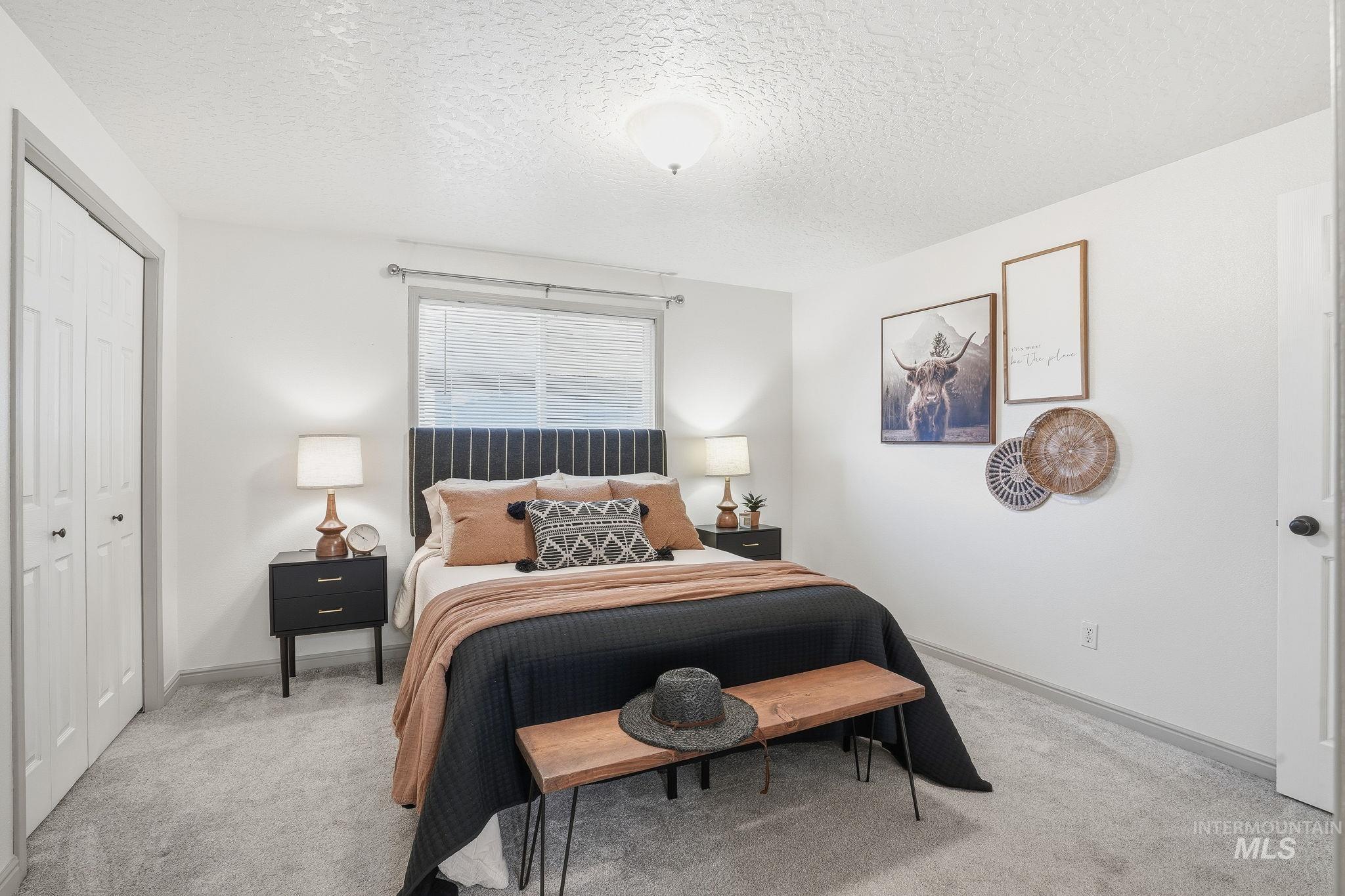 Carpeted bedroom featuring a textured ceiling and a closet