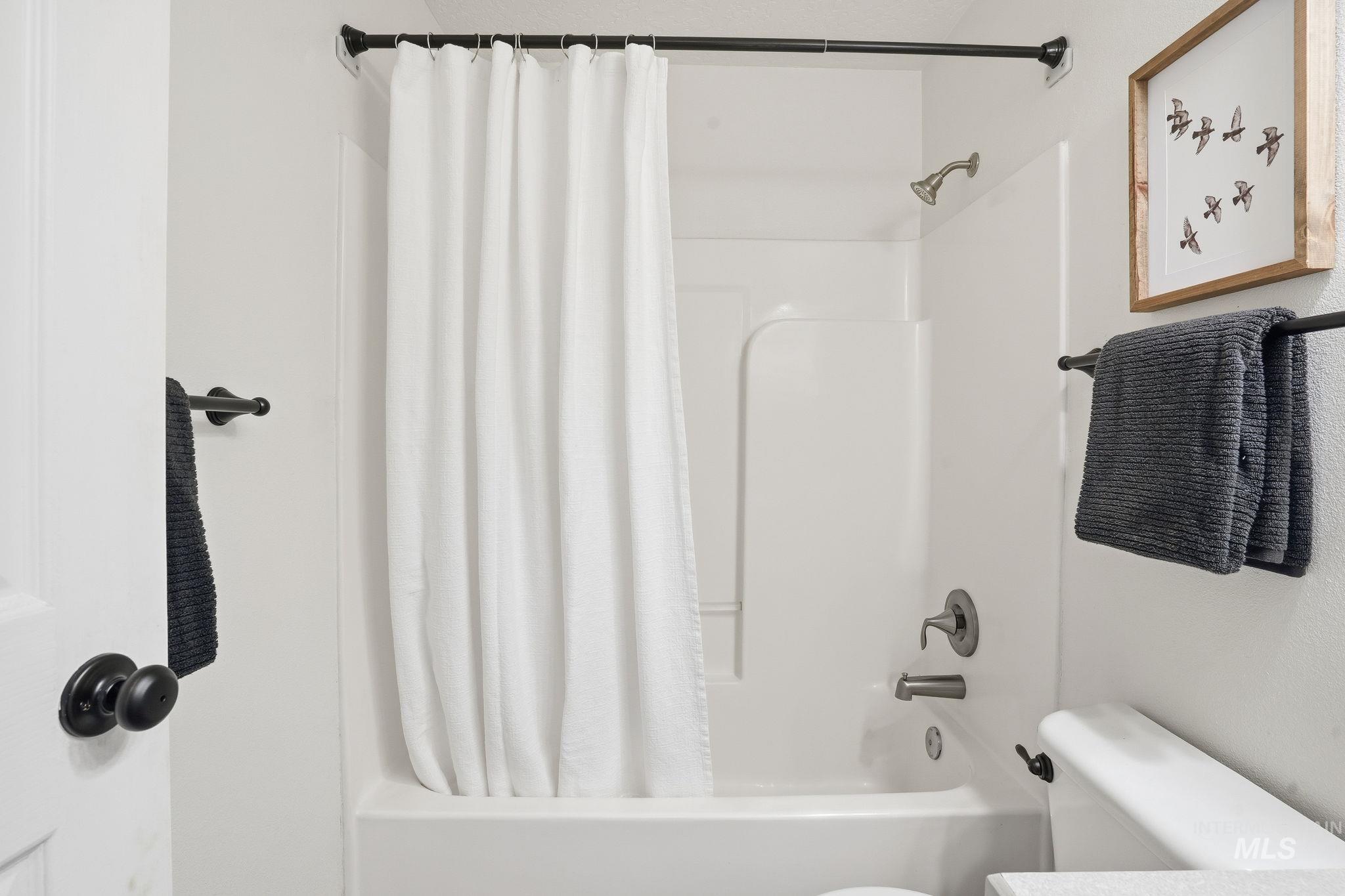 Full bath featuring shower / tub combo and toilet