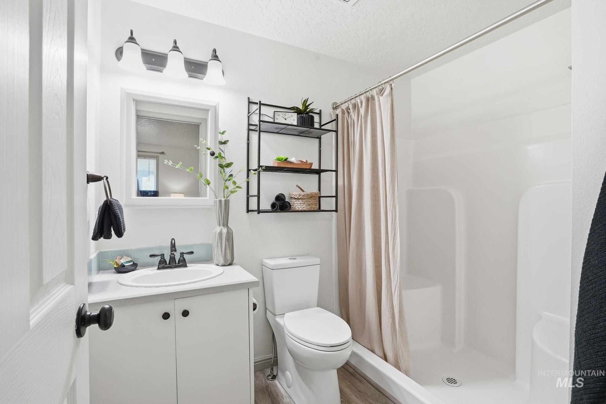 Bathroom featuring a stall shower, vanity, and a textured ceiling
