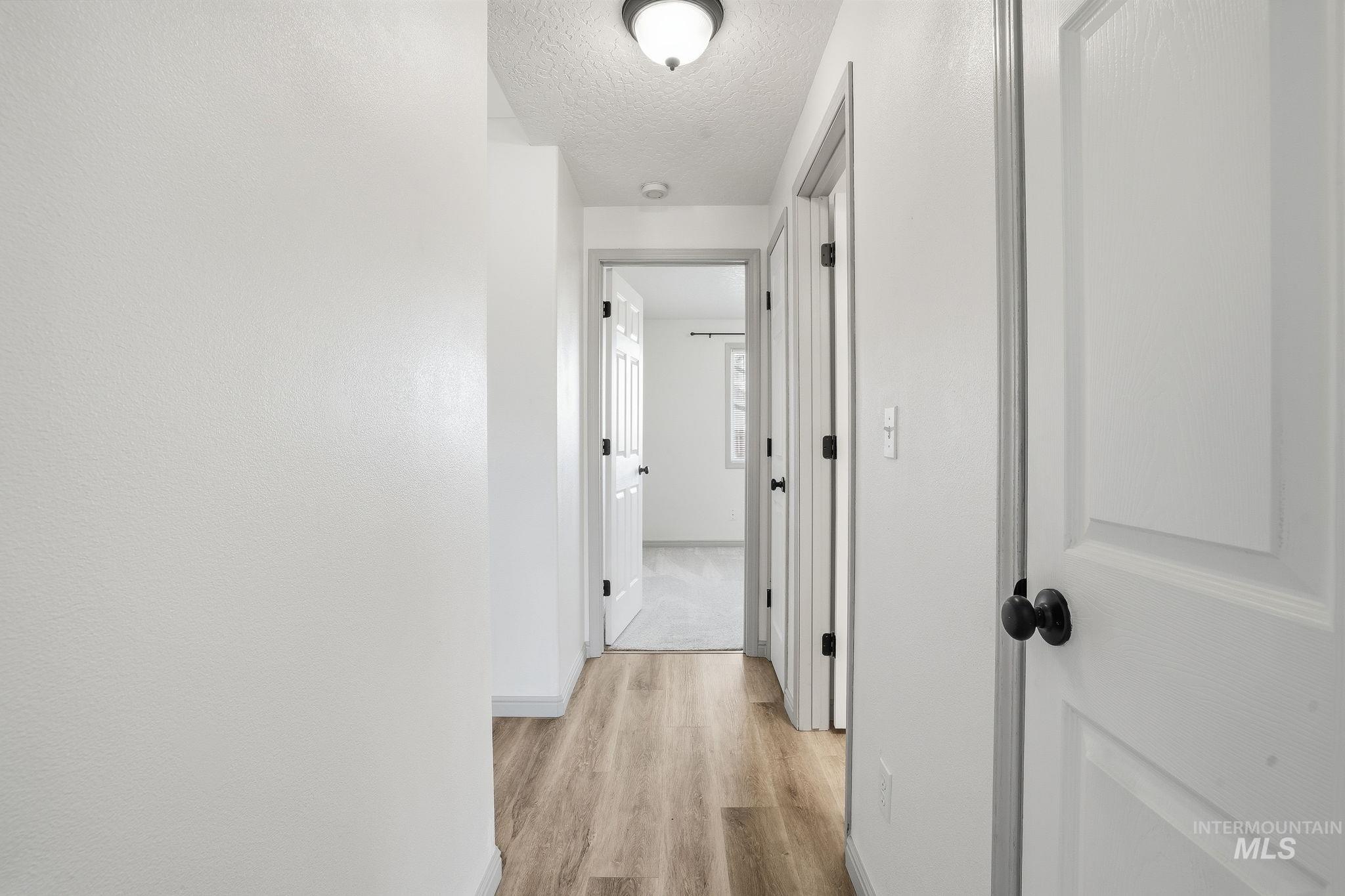 Corridor featuring light wood finished floors and a textured ceiling