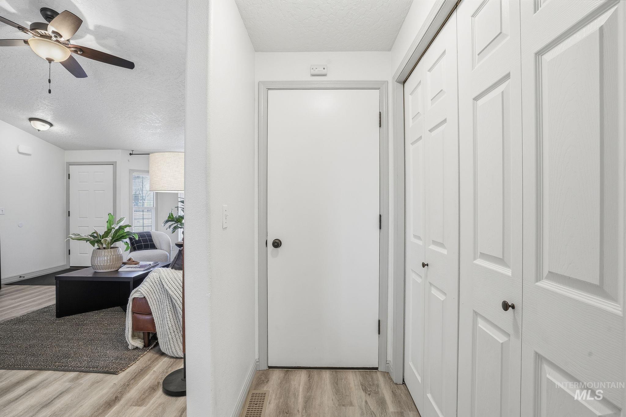 Hall with a textured ceiling and light wood-type flooring