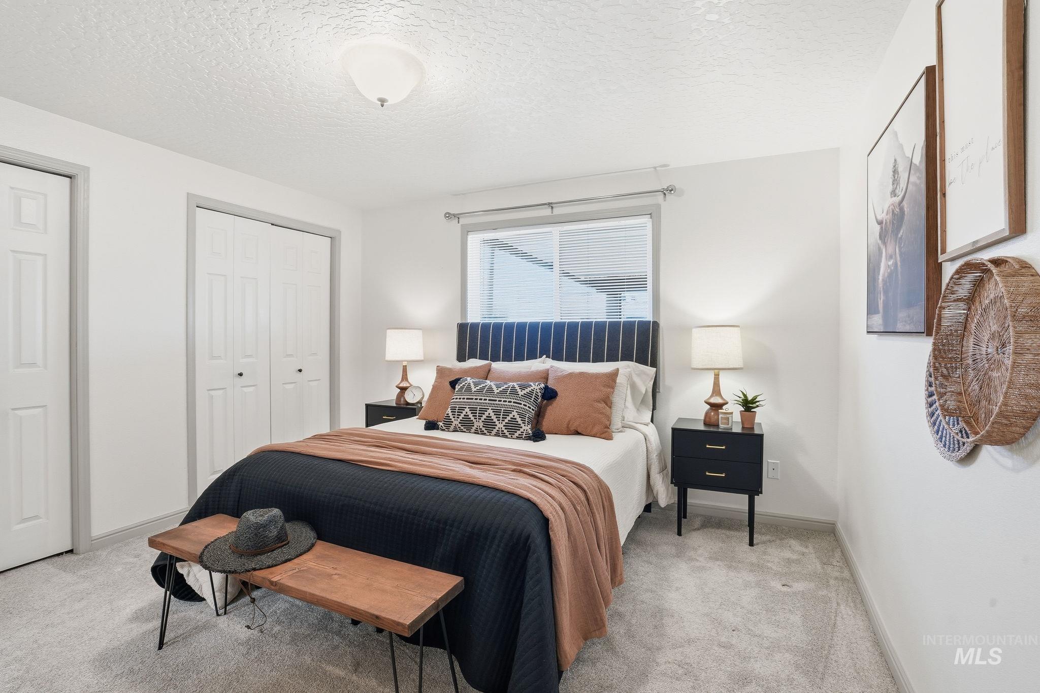 Bedroom with a textured ceiling, multiple closets, and carpet flooring