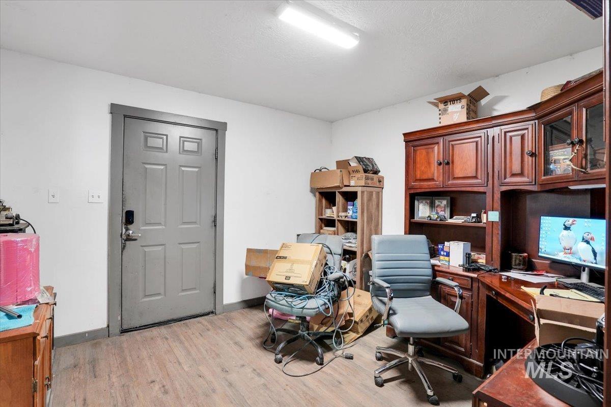 Office area with light wood-type flooring and a textured ceiling