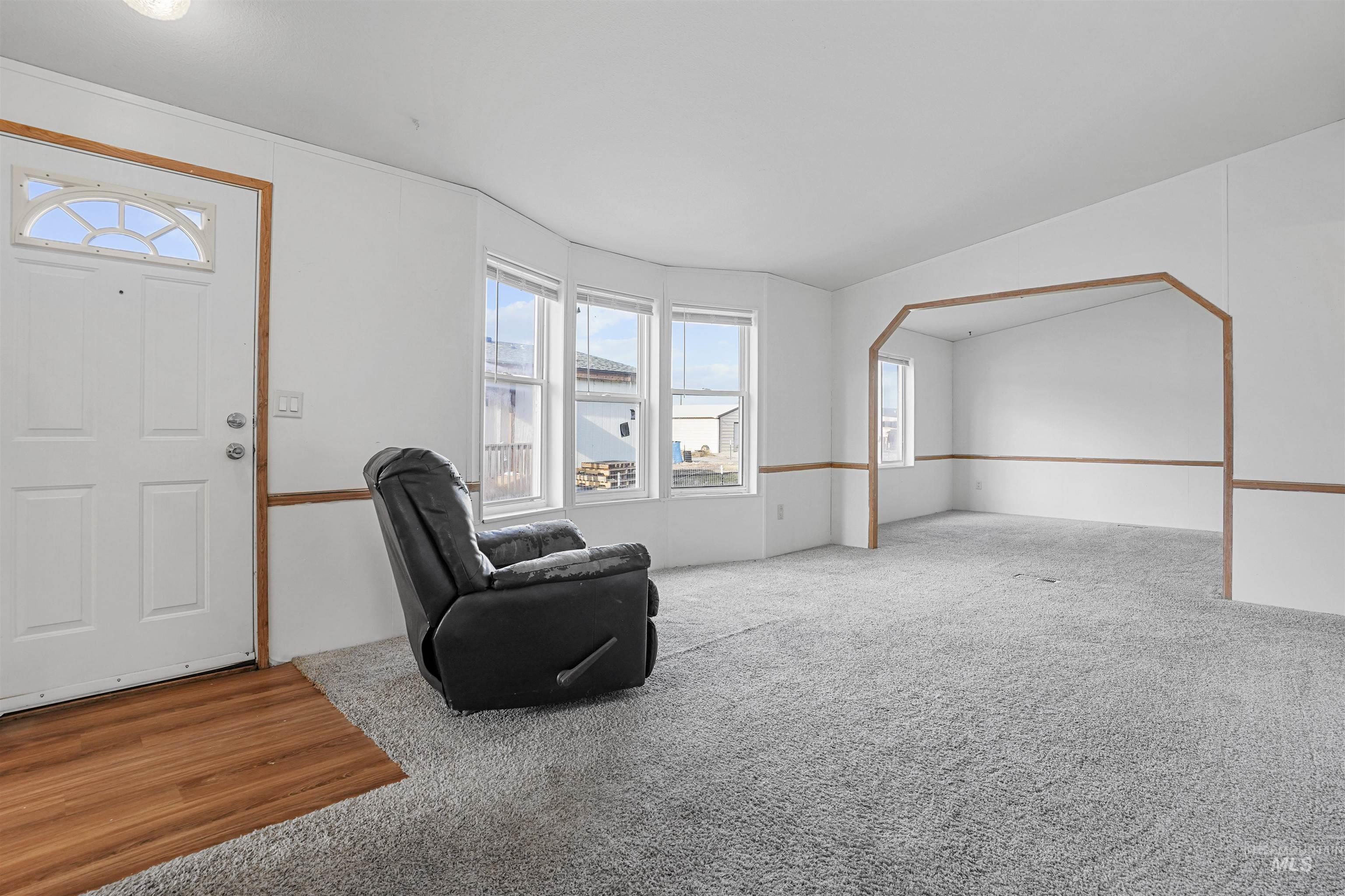 Unfurnished room with carpet flooring, arched walkways, and lofted ceiling