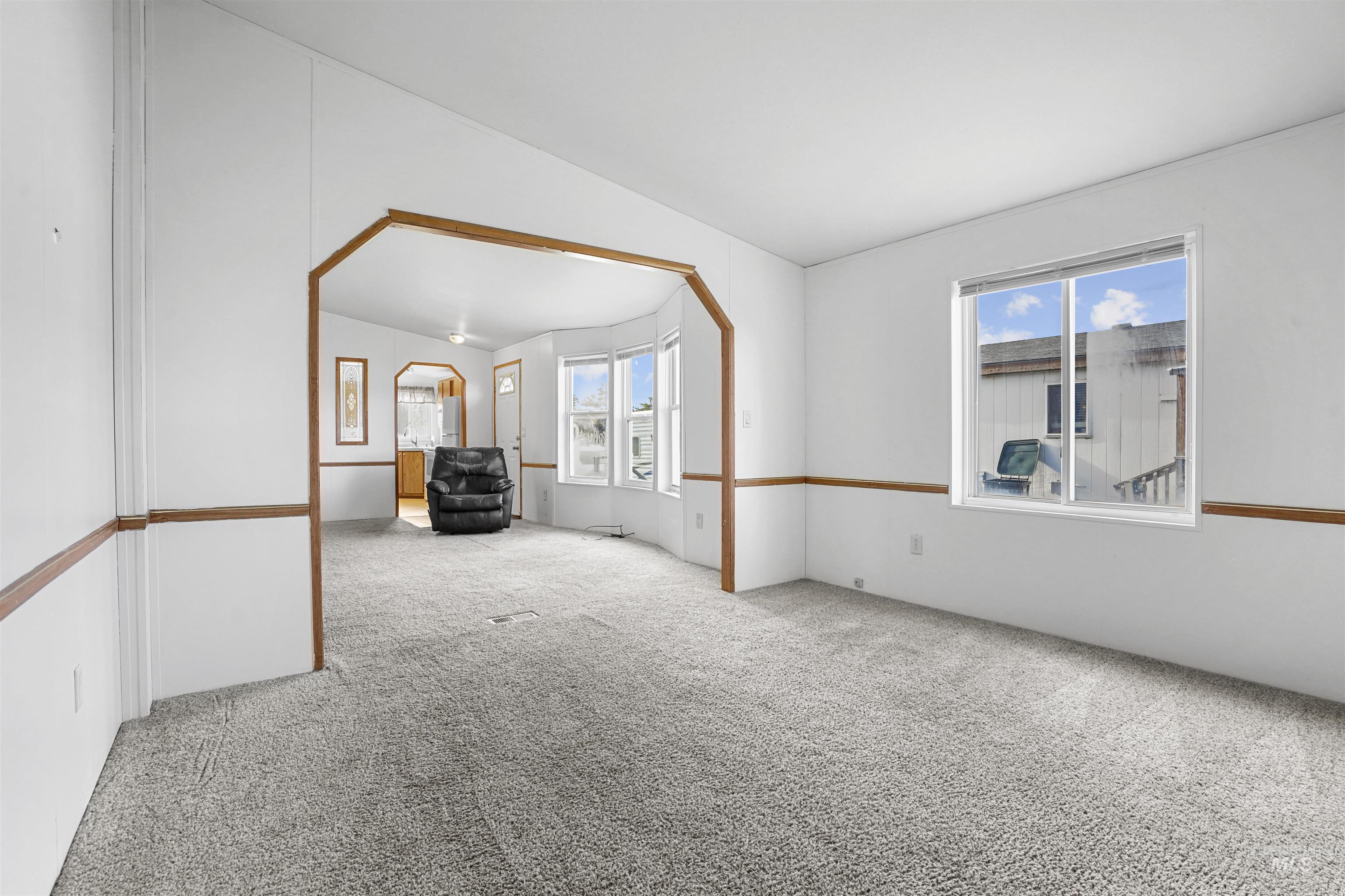 Empty room featuring vaulted ceiling and carpet
