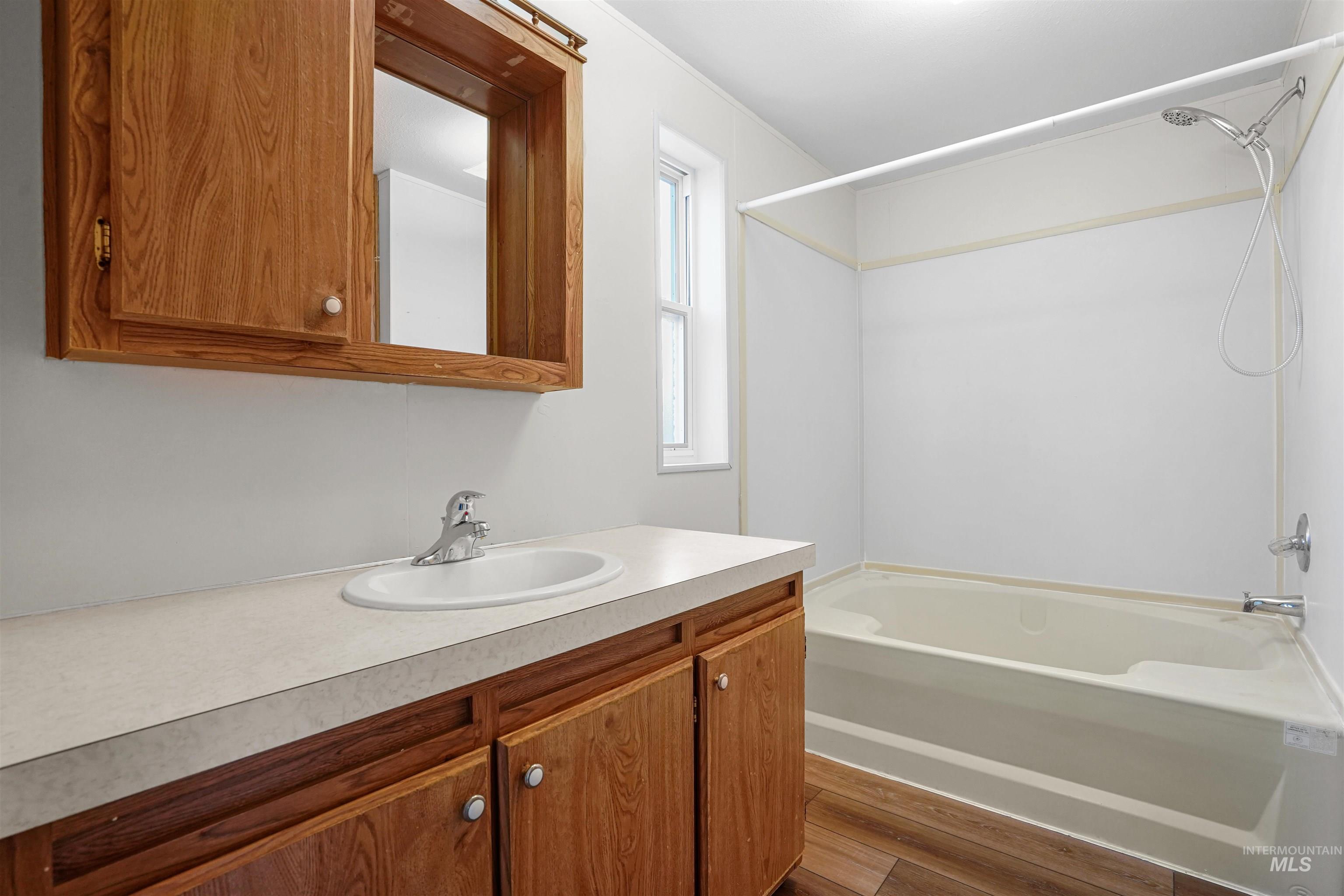 Full bath featuring shower / bath combination, vanity, and dark wood finished floors