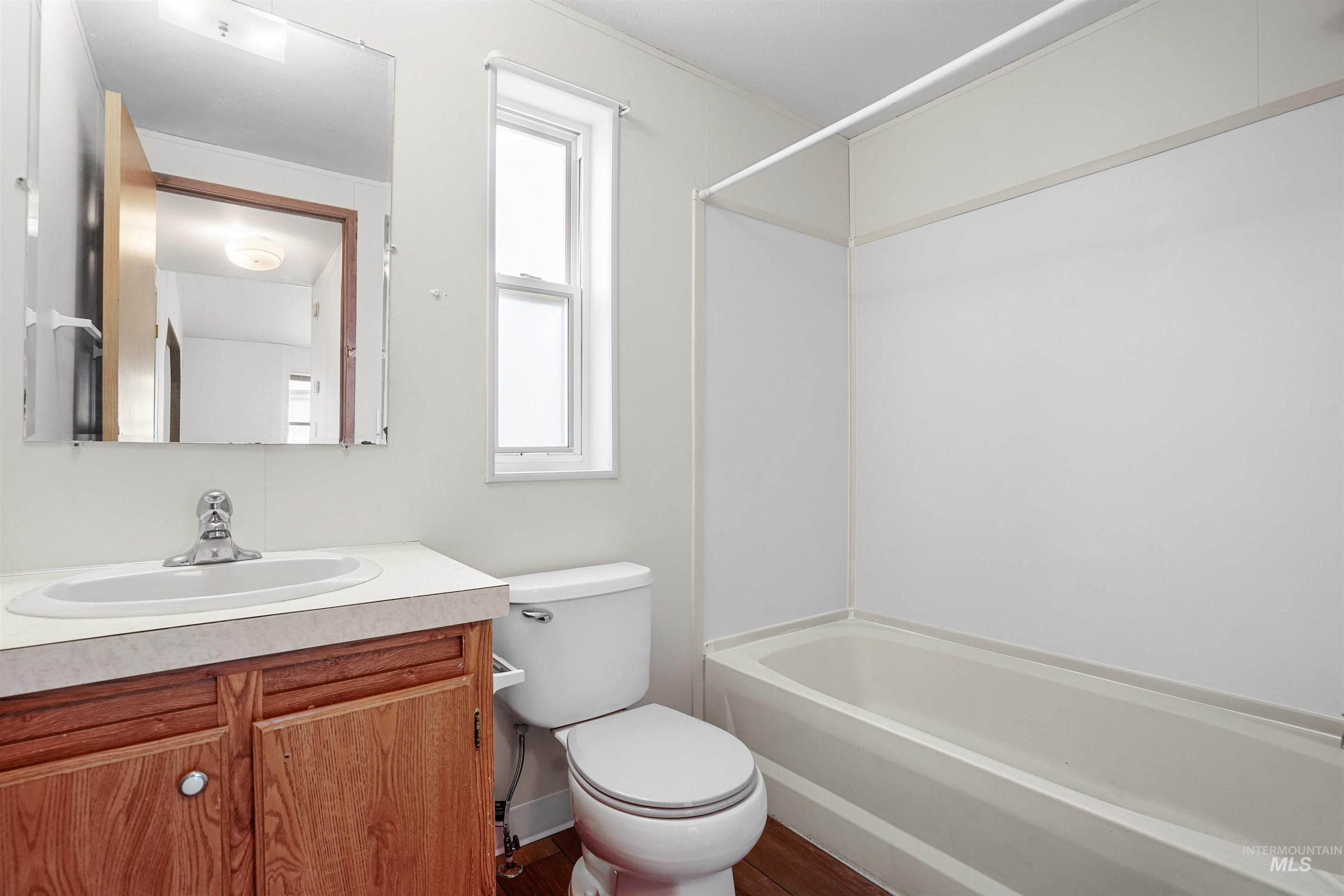 Bathroom with vanity, bathtub / shower combination, and dark wood-style flooring