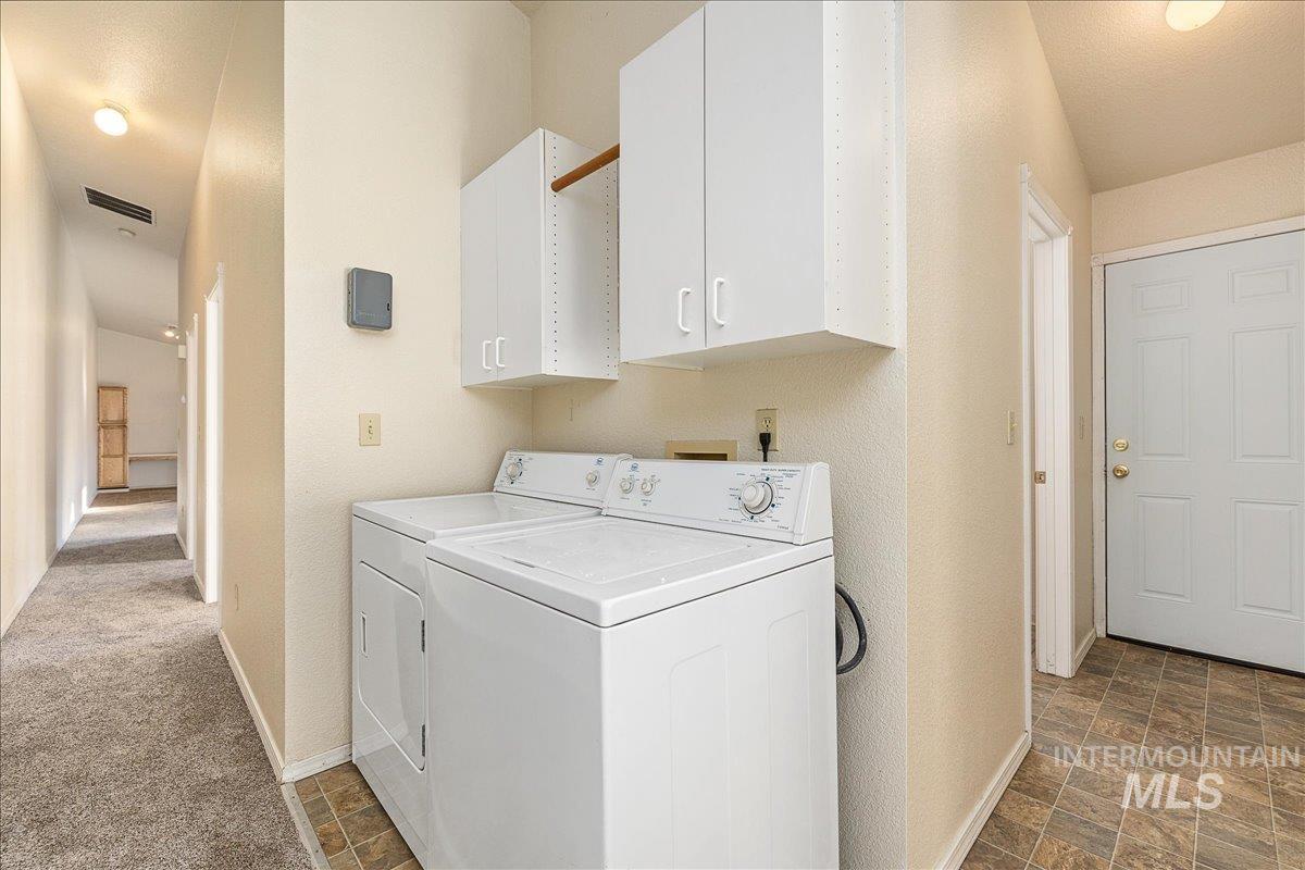 Washroom with cabinet space, separate washer and dryer, and stone finish floors