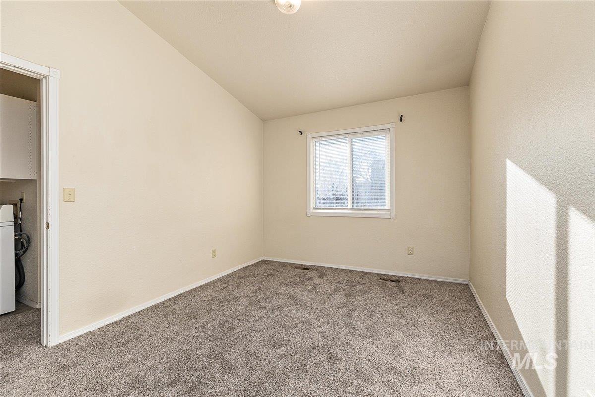 Unfurnished room with vaulted ceiling, carpet floors, and washer / clothes dryer
