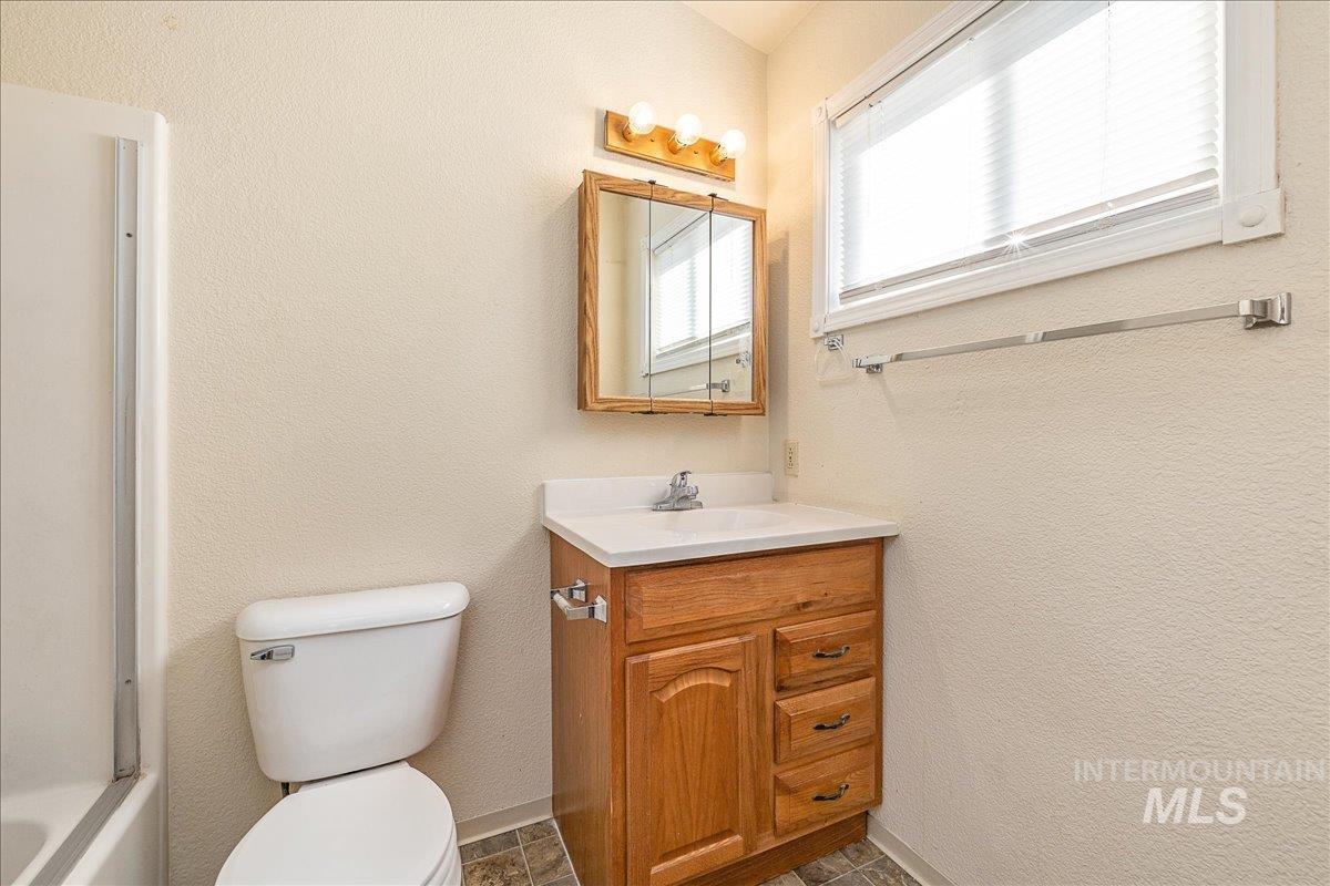 Bathroom featuring a textured wall, vanity, and tub / shower combination