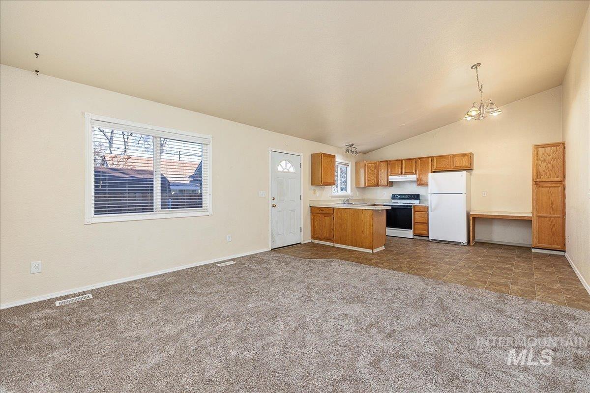 Kitchen with open floor plan, light countertops, white appliances, dark colored carpet, and brown cabinetry
