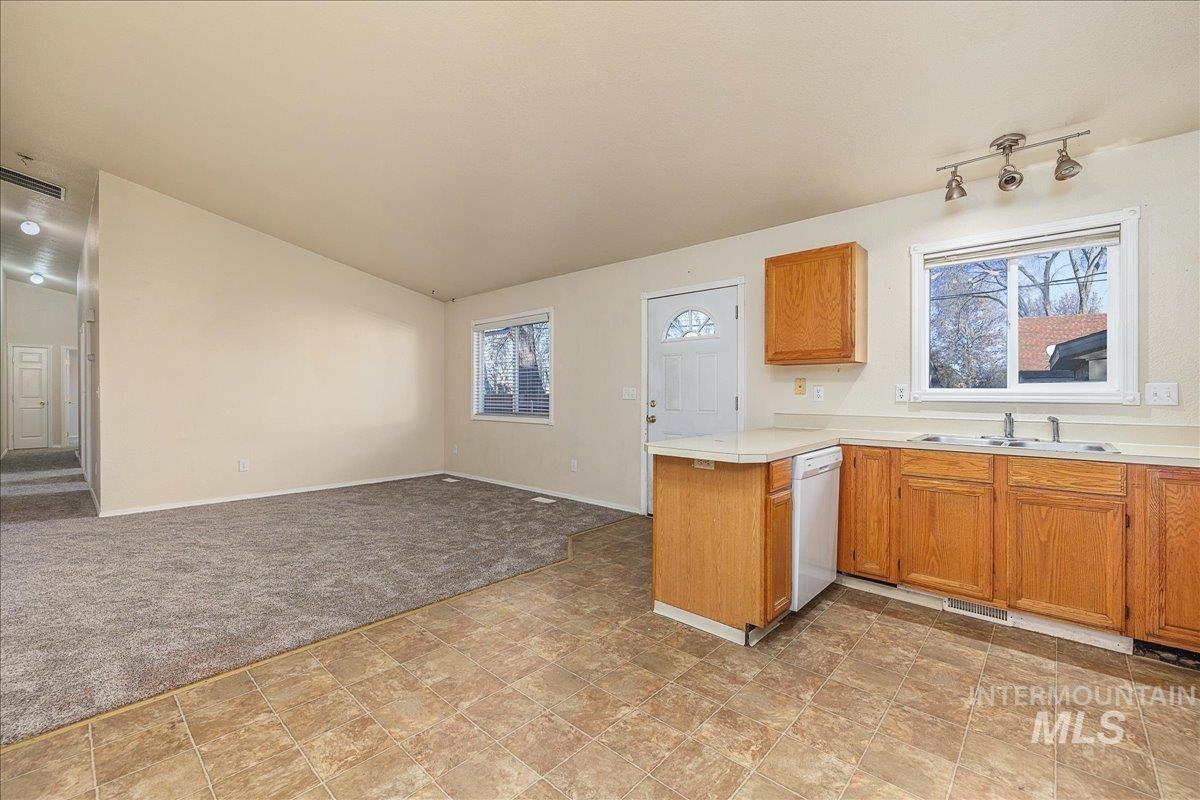 Kitchen with open floor plan, light countertops, brown cabinetry, a peninsula, and healthy amount of natural light
