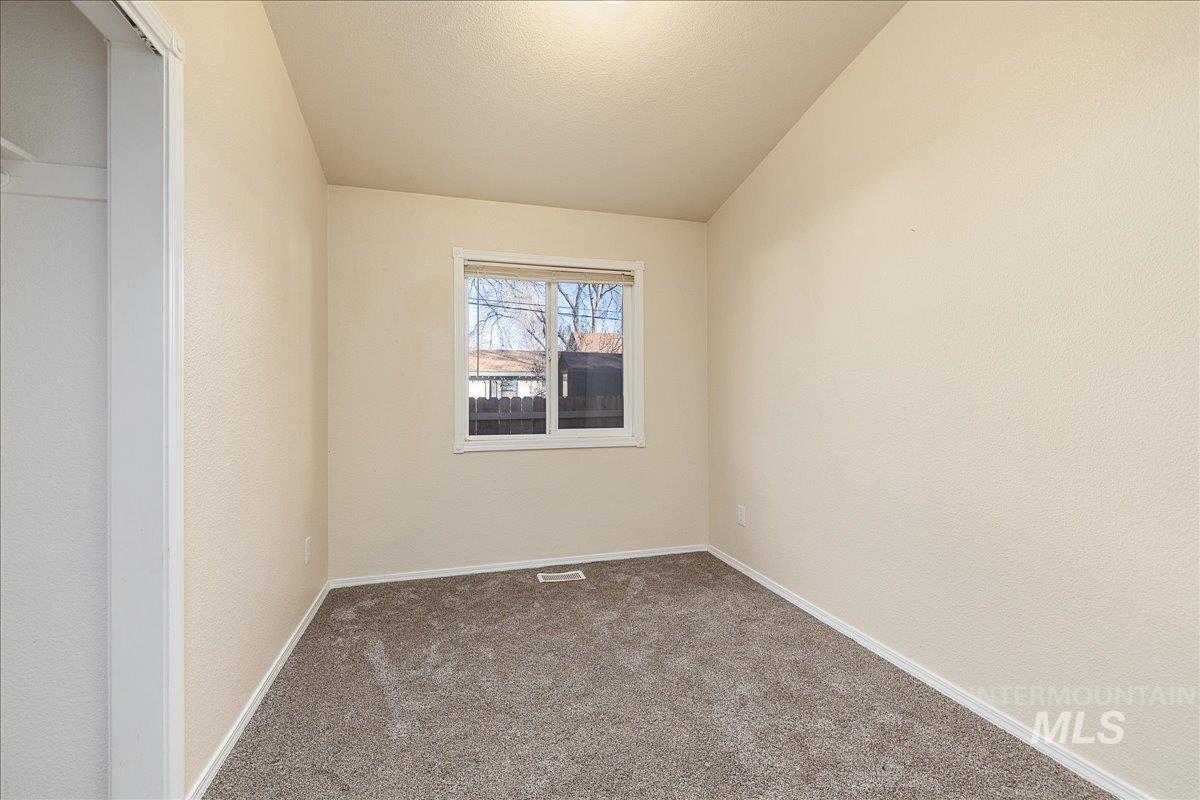 Carpeted spare room featuring baseboards