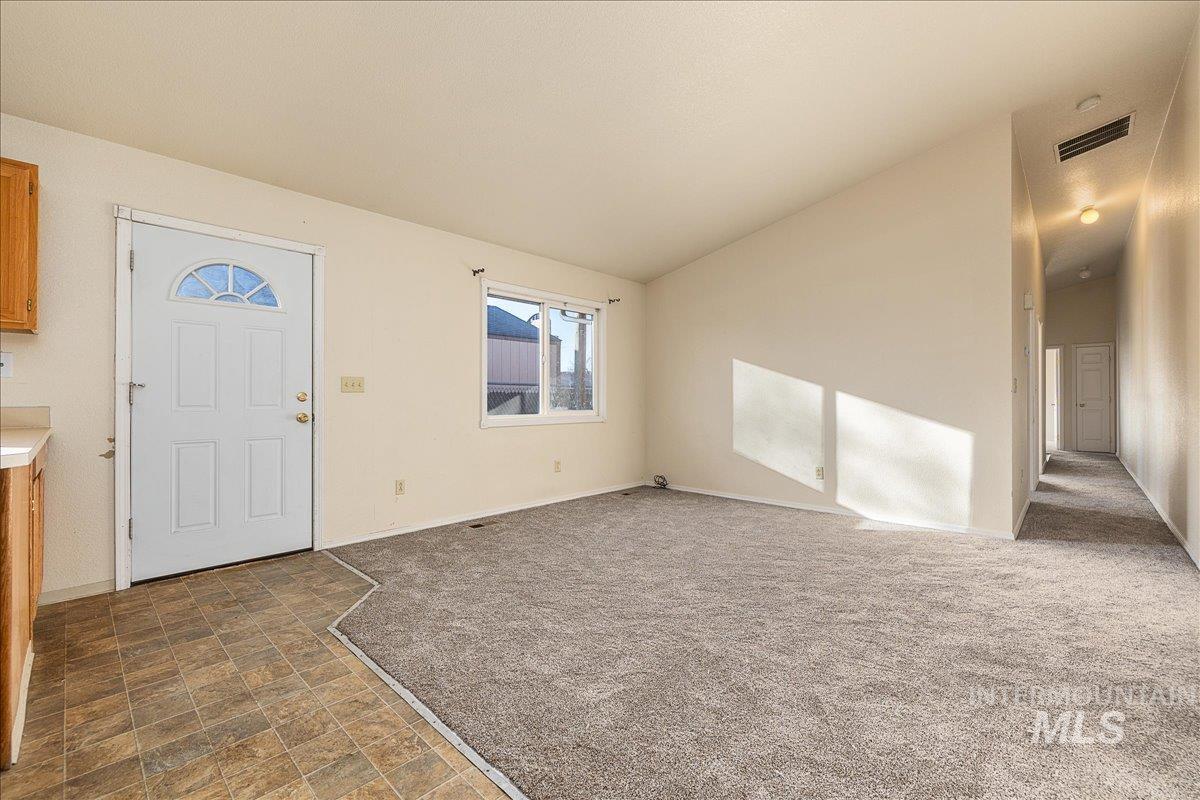 Entryway with vaulted ceiling, dark colored carpet, and stone finish floors