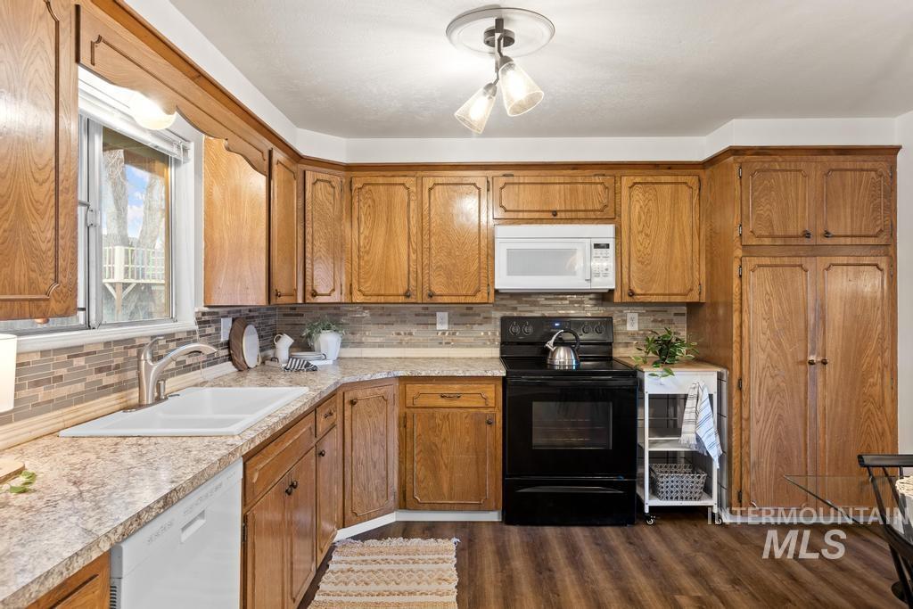Kitchen featuring brown cabinetry, white appliances, and light countertops