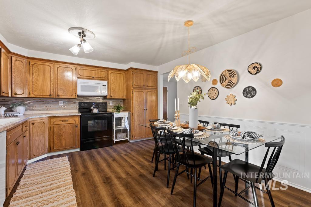 Kitchen featuring brown cabinetry, electric range, light countertops, dark wood-type flooring, and pendant lighting