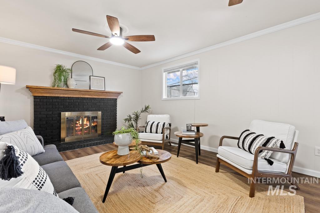 Living room with ceiling fan, a fireplace, crown molding, and wood finished floors