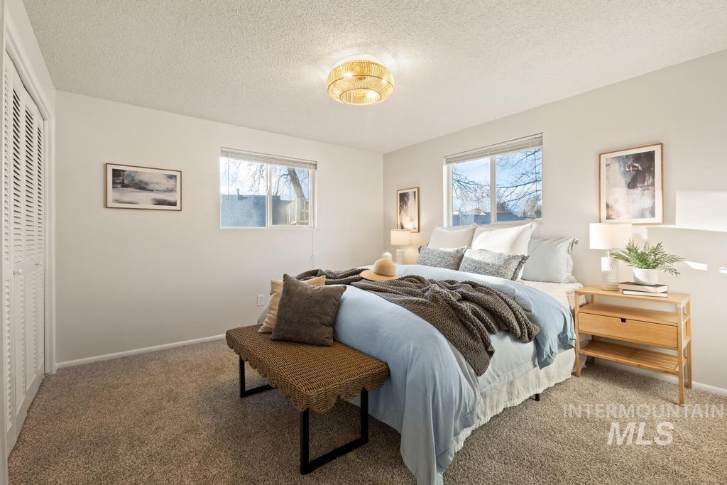 Bedroom with multiple windows, carpet flooring, a textured ceiling, and a closet