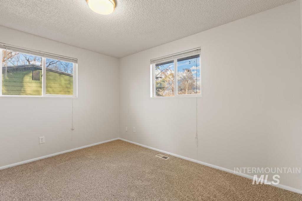 Unfurnished room with a textured ceiling, carpet, and healthy amount of natural light