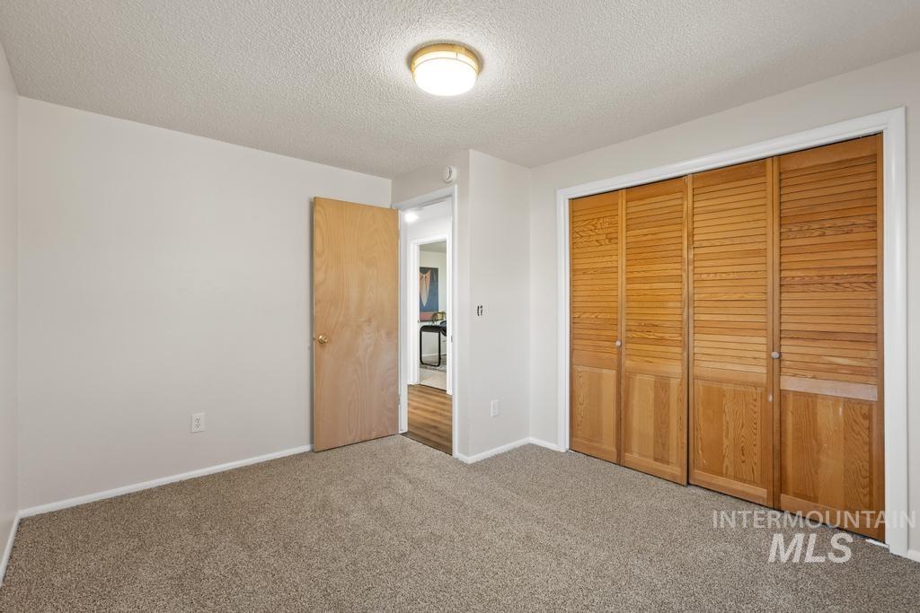 Unfurnished bedroom featuring a textured ceiling, a closet, and carpet