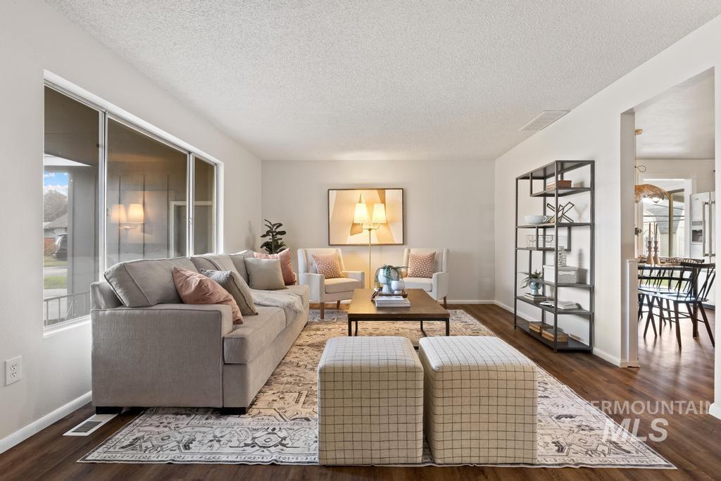 Living room with a textured ceiling, healthy amount of natural light, and dark wood-style flooring