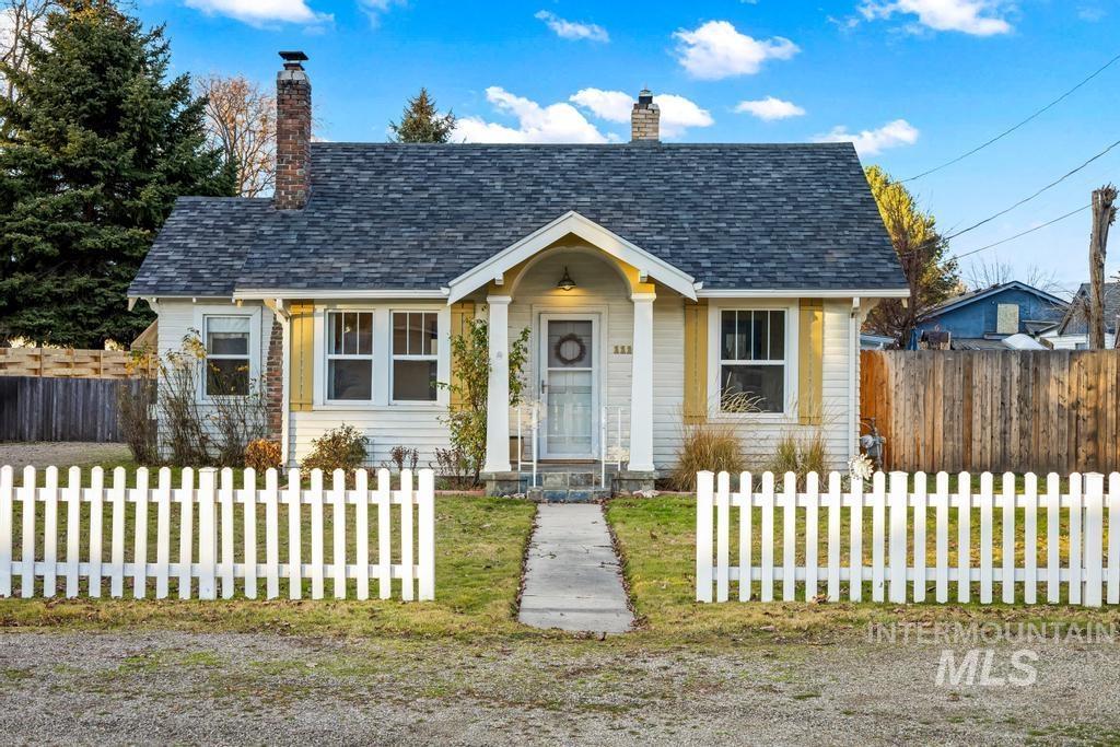 View of front of home featuring a chimney, a fenced front yard, and a shingled roof