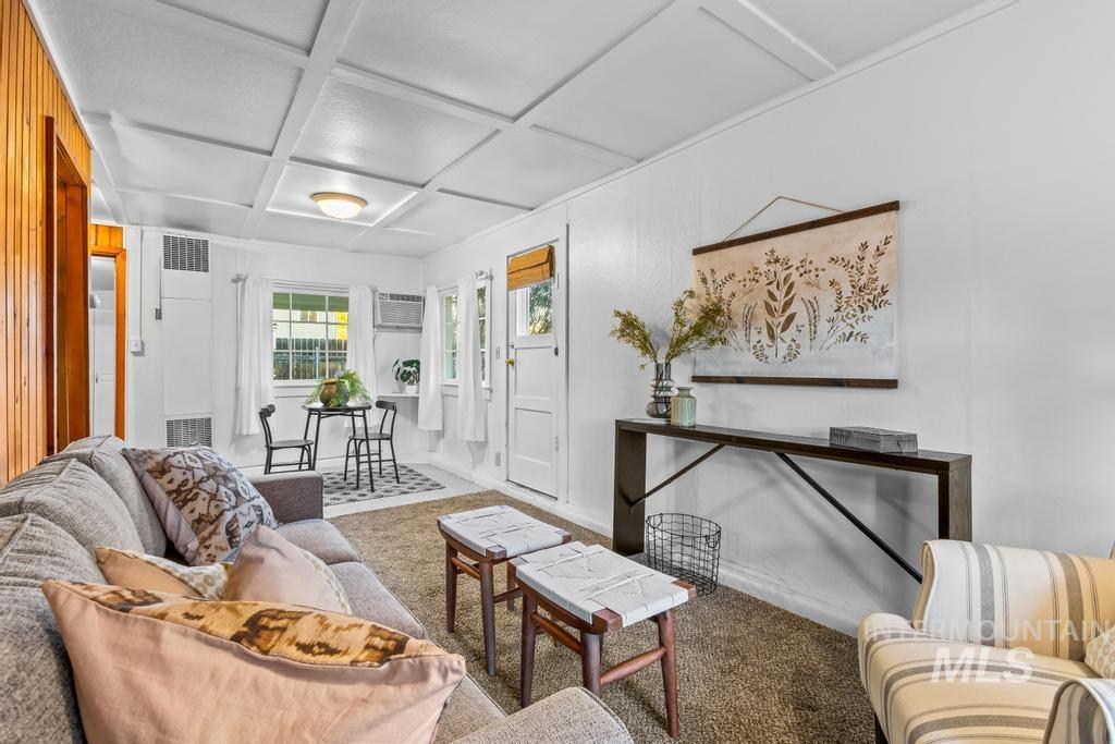 Living room with coffered ceiling, carpet floors, and a heating unit