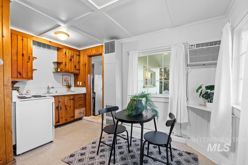 Kitchen featuring light countertops, open shelves, brown cabinetry, white electric range, and a wall unit AC