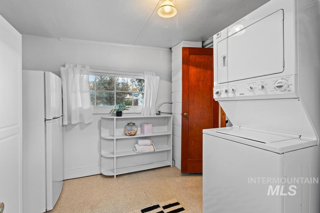 Laundry room with light floors and estacked washer and dryer
