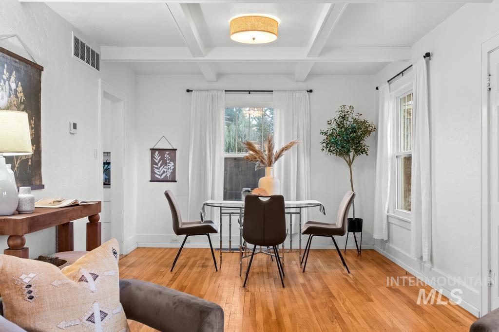 Dining area featuring beam ceiling, light wood-style floors, and coffered ceiling