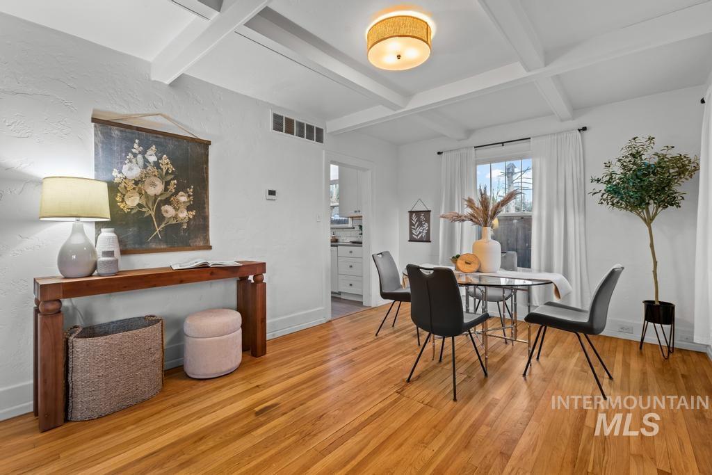 Dining room with beamed ceiling, light wood-style flooring, and coffered ceiling