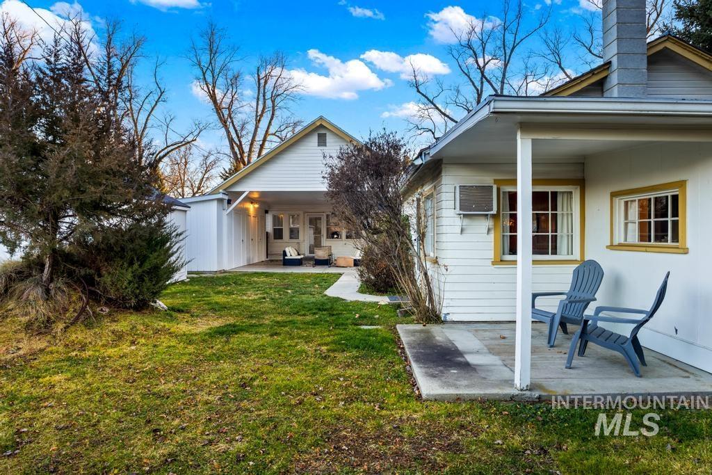 Rear view of house featuring a patio area, a lawn, a wall unit AC, and a chimney