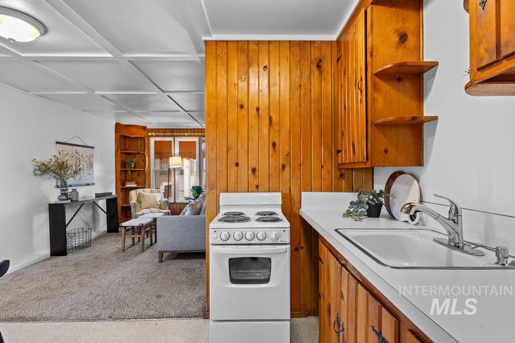 Kitchen with brown cabinets, white electric stove, light countertops, light carpet, and built in features