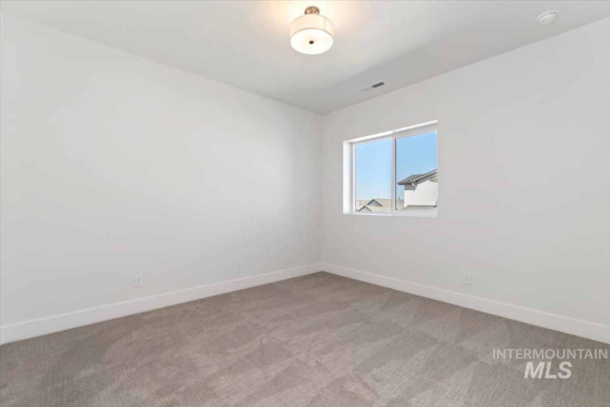 Unfurnished room featuring baseboards and light carpet