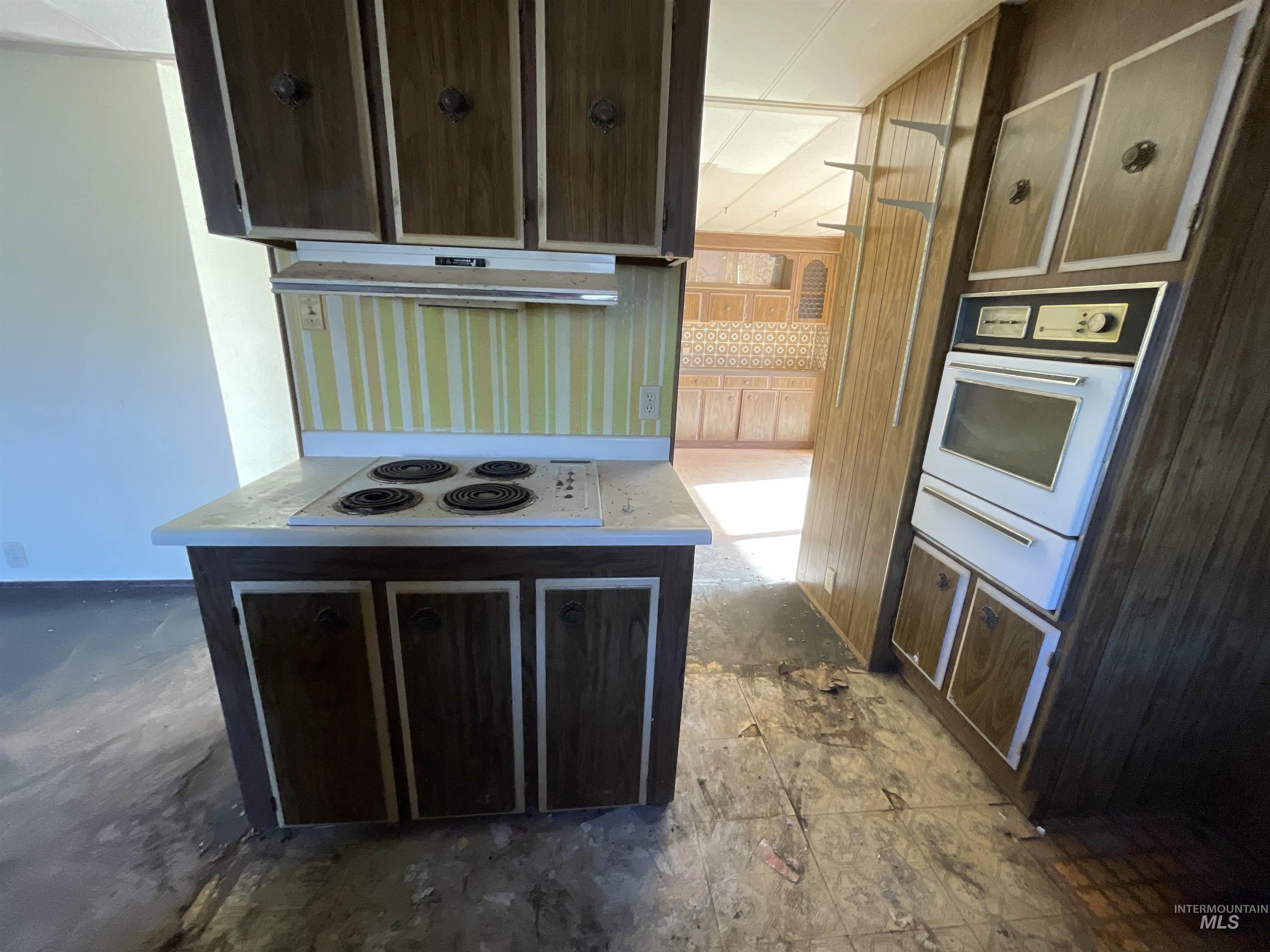 Kitchen featuring dark brown cabinets, white appliances, a warming drawer, and light countertops