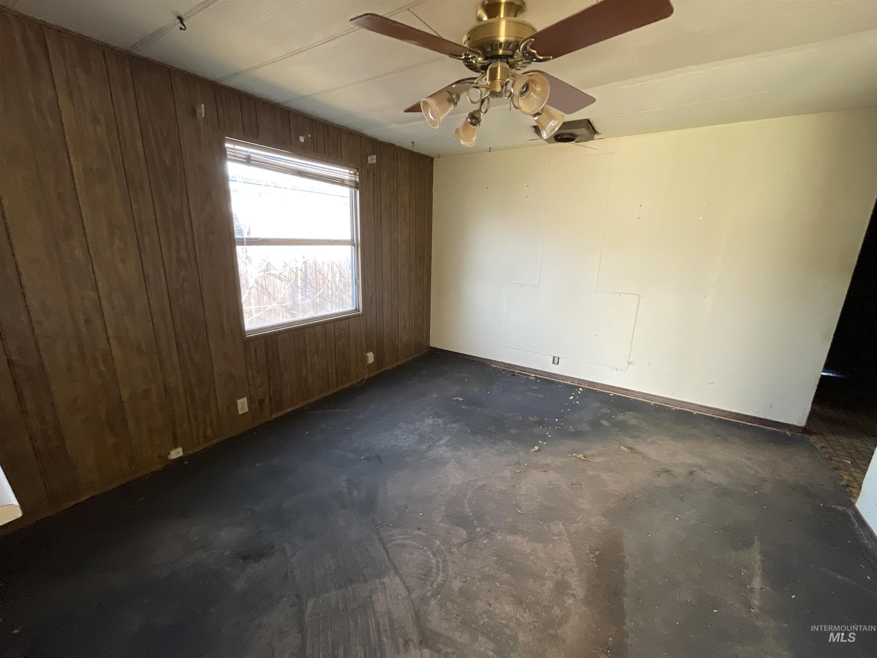 Empty room featuring wooden walls and ceiling fan