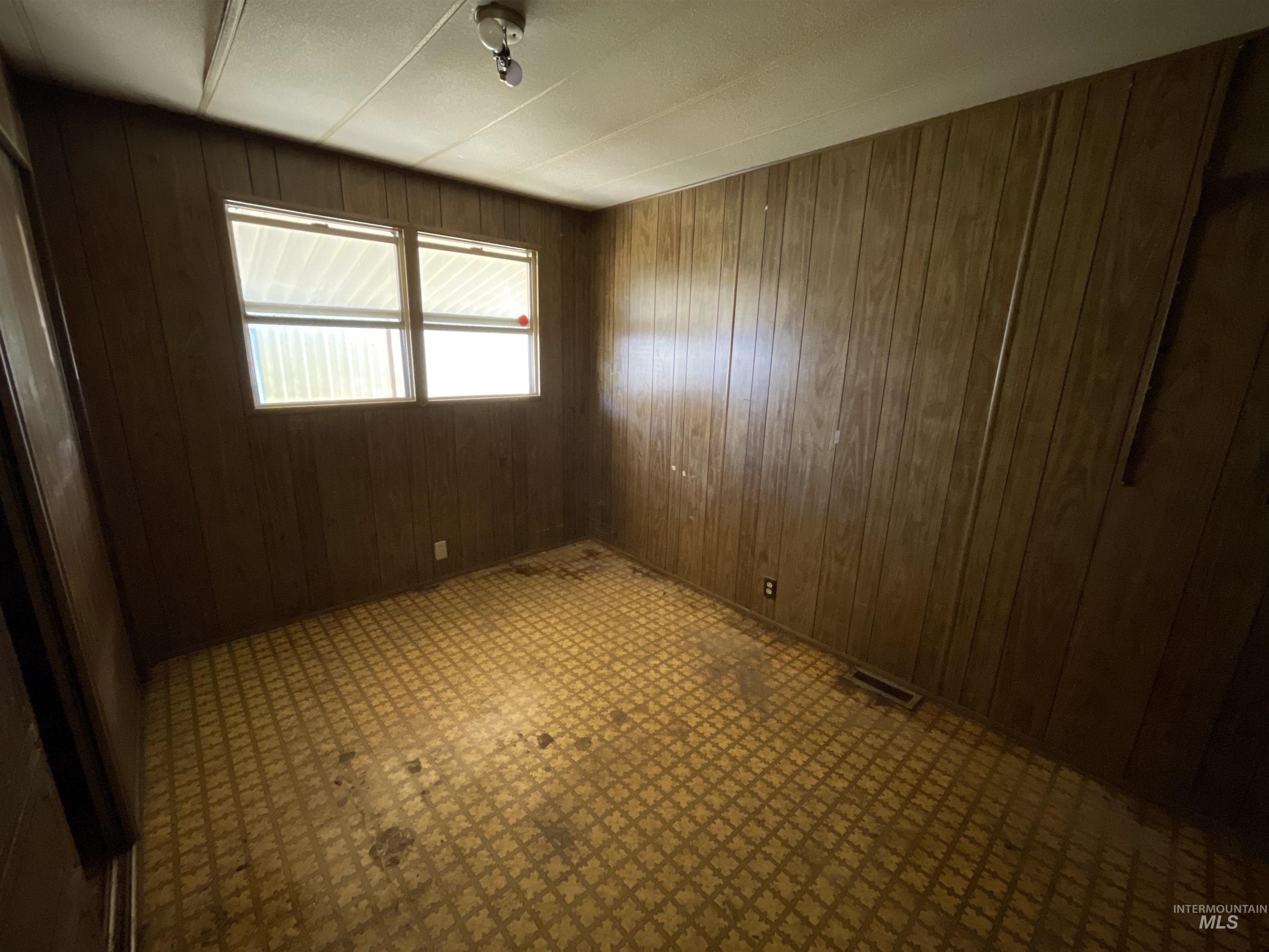 Spare room with tile patterned floors and wooden walls