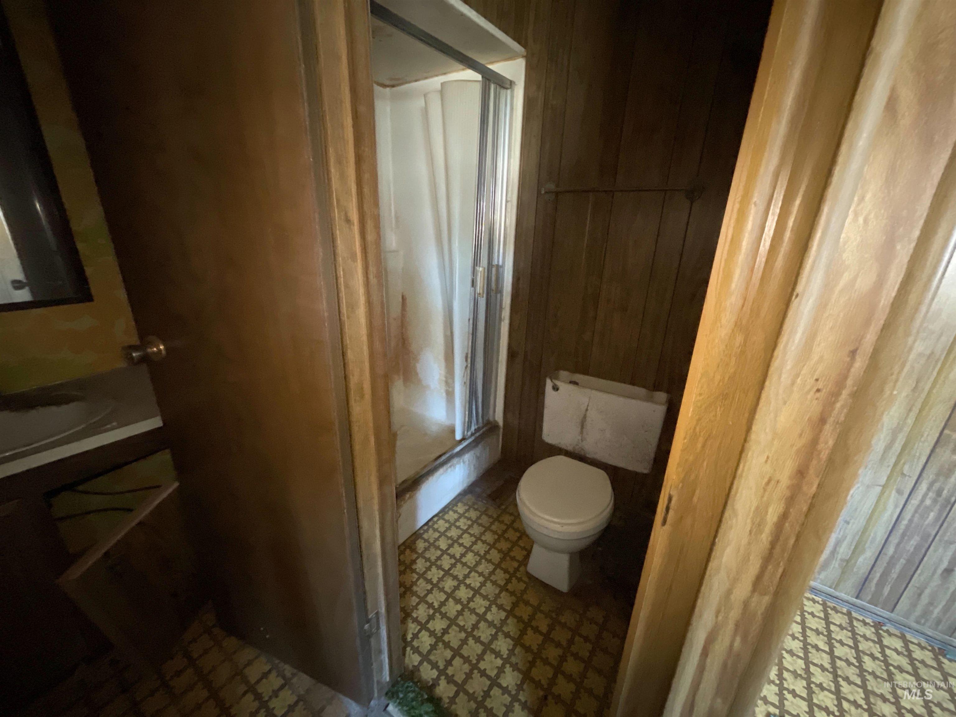 Full bathroom featuring vanity, wooden walls, tile patterned floors, and a shower