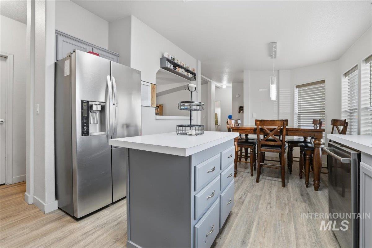 Kitchen featuring appliances with stainless steel finishes, light countertops, a kitchen island, and hanging light fixtures
