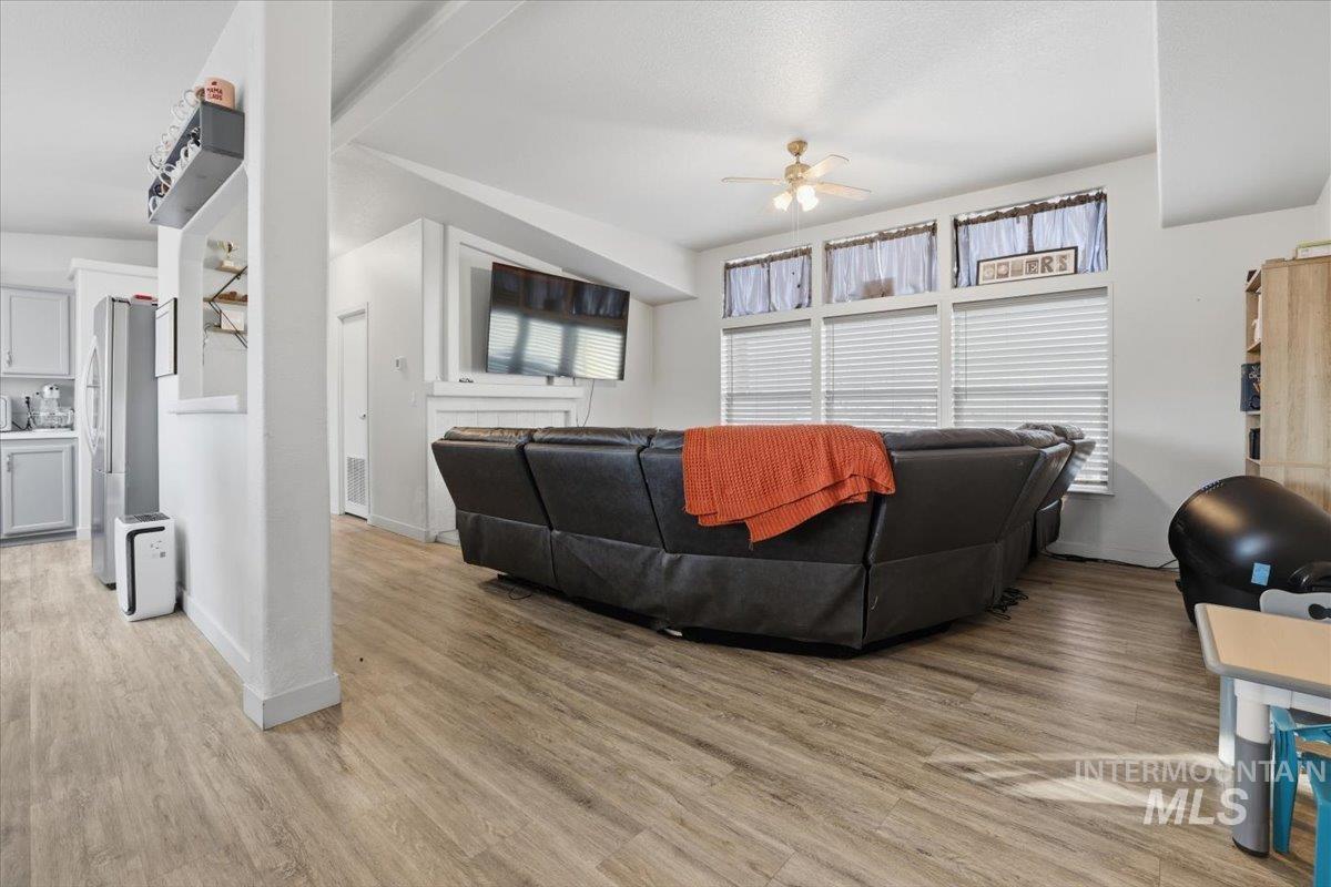 Living room with a ceiling fan, light wood-style floors, and plenty of natural light