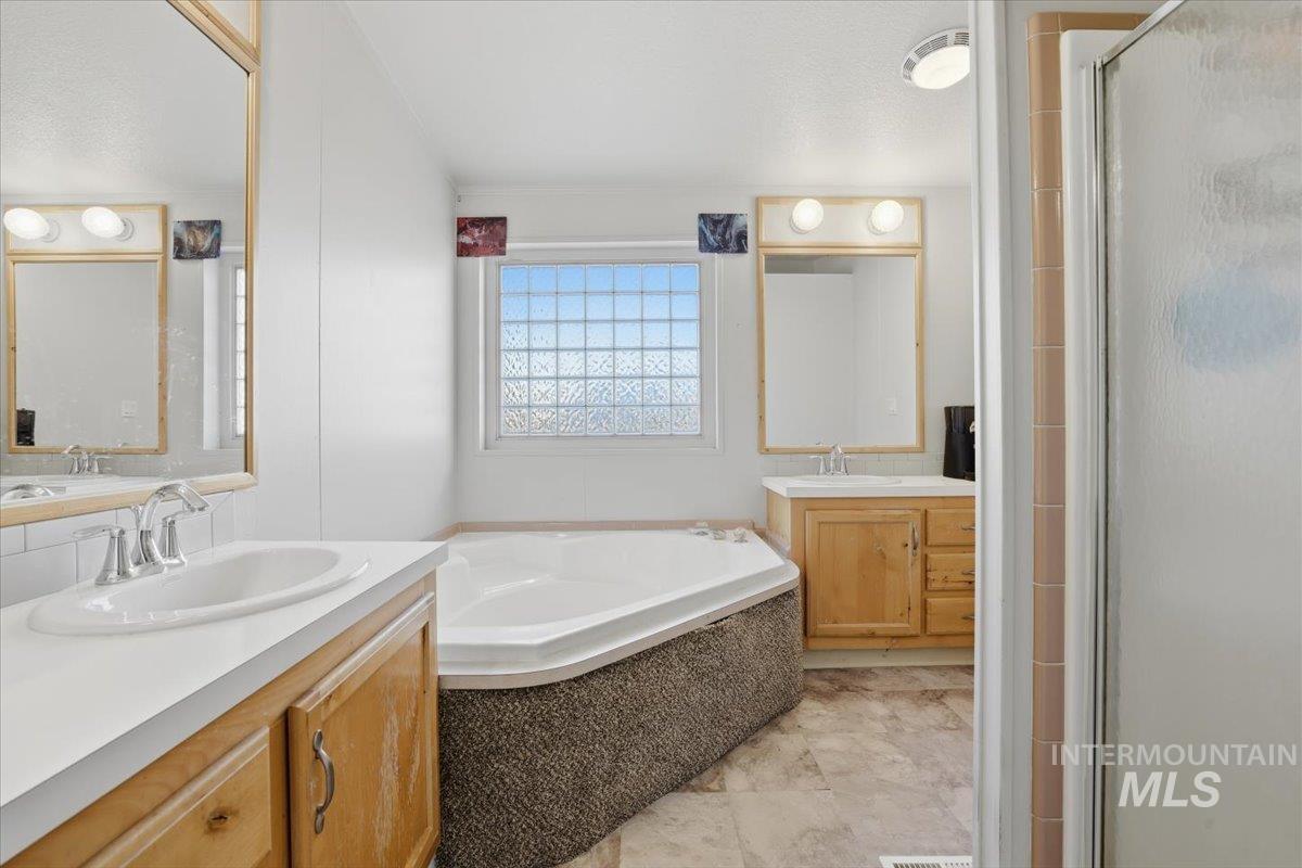 Bathroom featuring two vanities, a shower stall, and a bath