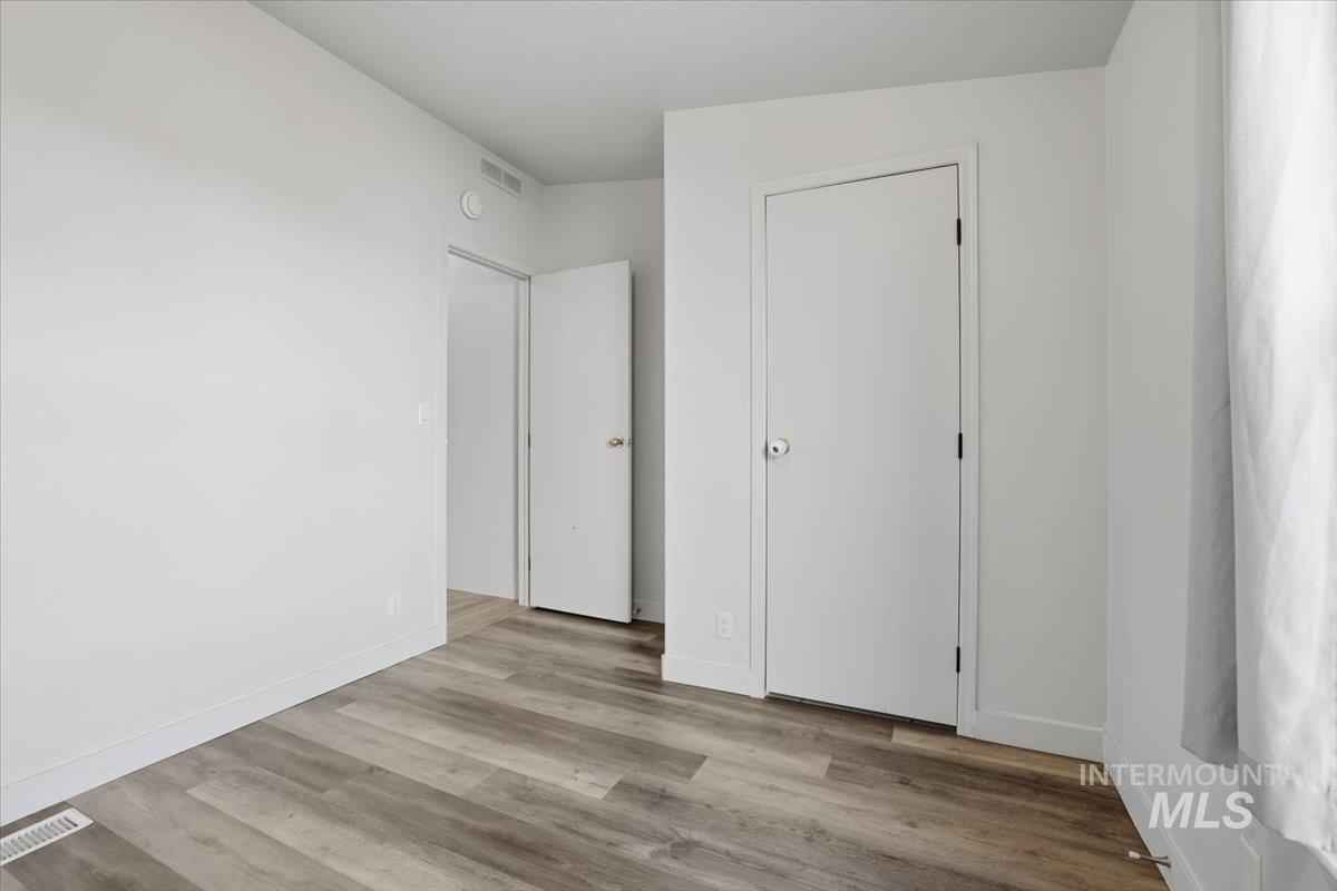 Unfurnished bedroom featuring light wood finished floors and baseboards