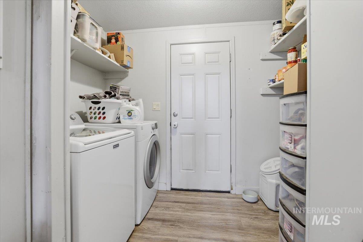 Laundry area with light wood finished floors, separate washer and dryer, and a textured ceiling